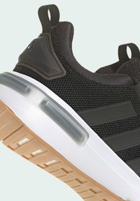 Black textile sneaker with mesh upper, rubber sole, clear cushioning, and three black stripes. Features a white midsole and rubber accents.