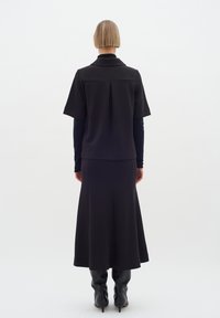 Musta kaksiosainen asu, joka koostuu lyhythihaisesta collarellista paidasta ja pitkästä, valuva hameesta. Sileä rakenne ja minimalistinen muotoilu.