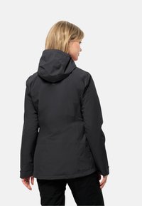 Giacca nera impermeabile con cappuccio, tessuto testurizzato e polsini regolabili. Presenta una vita arricciata per una silhouette aderente.