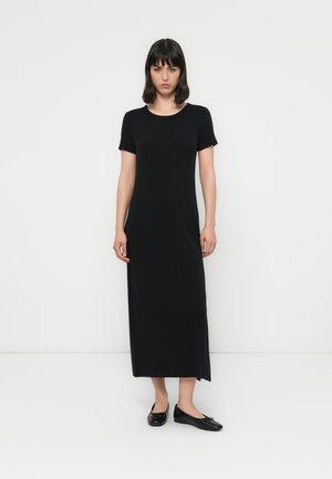 Black, knee-length, short-sleeve dress with a round neckline and side slits; smooth, lightweight fabric; paired with black flats.