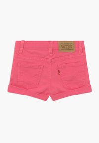 Růžové džíny šortky s ohrnutými lemy, obsahující dvě zadní kapsy a hnědou koženou štítku s logem značky na pase.