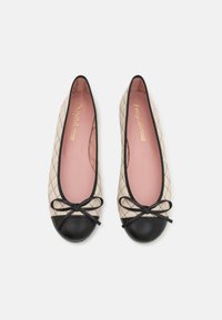 Ballerinas mit einem beigen, gesteppten Äußeren, schwarzem Zehenkappen und einem schwarzen Schleifenakzent. Das Innere ist hellrosa mit dem Markenlogo in Gold.