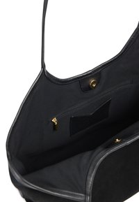 Sac fourre-tout noir avec un extérieur en suede doux, des accents en cuir et une fermeture à pression magnétique. L'intérieur comprend une poche zippée et une poche plaquée.