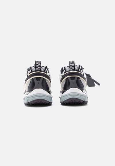 Ζευγάρι αθλητικών παπουτσιών σε μαύρο, λευκό και γκρι, που φαίνεται από πίσω σε λευκό φόντο.