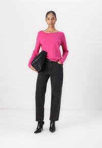 Rosa långärmad topp, svarta högmidjade jeans, svarta spetsiga klackskor och en svart clutchväska. Slät textur, avslappnad passform.