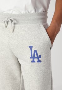 Graue Jogginghose mit einem gerippten Bund und verstellbarem Kordelzug. Zeigt ein auffälliges blaues "LA"-Logo am linken Oberschenkel. Weicher Stoff.