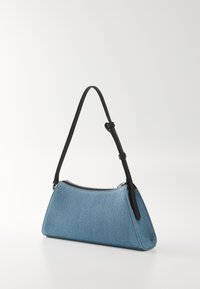Bolsa de denim azul em forma triangular, com alça de couro preta, fecho de metal prateado e costuras em contraste. Textura suave com um design estruturado.