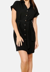 Czarna sukienka z paskiem, kołnierzykiem, krótkimi podwiniętymi rękawami i złotymi guzikami z przodu. Miękka, gładka tkanina o swobodnym kroju.