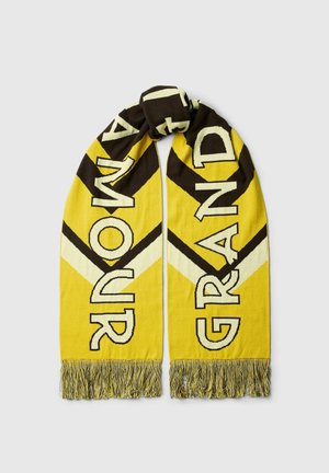 Sárga és fekete kötött sál széles átlós csíkokkal és rojtos végekkel, mindkét oldalán vastag betűkkel "RUNOMA" és "GRAND" felirattal.