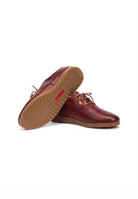 Zapatos de cuero burdeos con un acabado suave, diseño de cordones y una suela de goma marrón con un patrón texturizado.