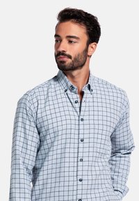 Grijze geruite shirt met een button-down kraag, voorzien van blauwe accenten, lange mouwen en een zak op de linkerkant van de borst.