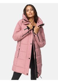 Gaiši rozā garais uzpūstais mētelis ar augstu apkakli, priekšējo rāvējslēdzēju un sānu kabatām; tam ir melnas akcenti un ūdensizturīga apdare.