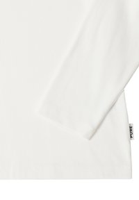 Biała, prążkowana koszula z długim rękawem z małą metką materiałową oznaczoną napisem "PURE" na bocznym szwie w pobliżu dołu.