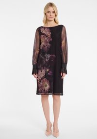 Schwarzes Kleid mit durchsichtigen langen Ärmeln, das lebendige Blumenmuster aufweist. Texturierte Bündchen mit Spitzenakzenten, knielanges Design.