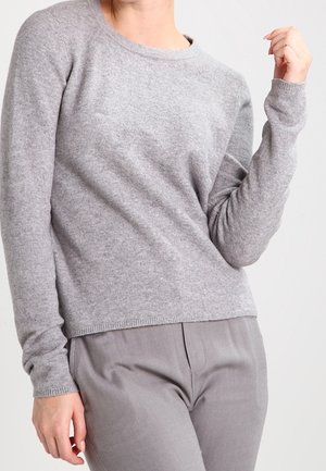 Maglione grigio a maglia con collo a giro e maniche lunghe. Struttura morbida, polsini e orlo a coste. Indossato con pantaloni grigi abbinati.