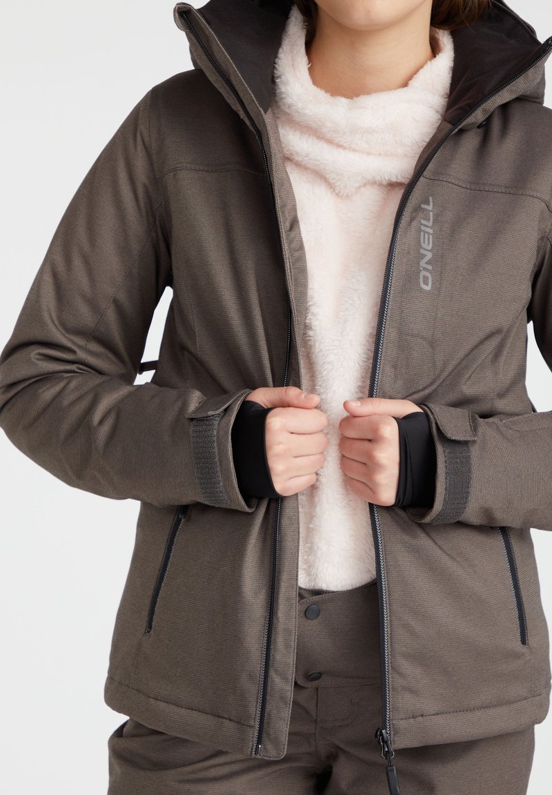 Braune Sportjacke mit Reißverschluss, ausgestattet mit einem weichen, rosa Fleece-Innenfutter, verstellbaren Bündchen und zwei Seitentaschen. Logos auf der Vorderseite.