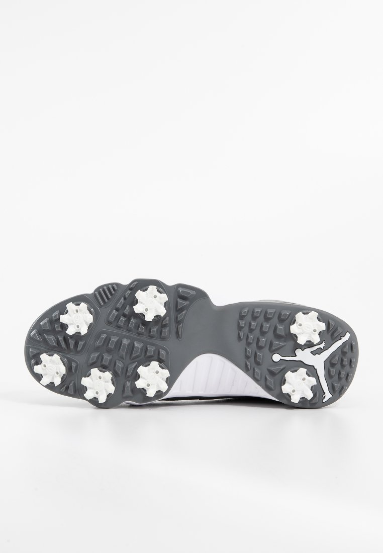 Suela de zapato de fútbol con una base de goma gris, clavos de tracción blancos y patrones texturizados, incluyendo un detalle del logo en el lateral.