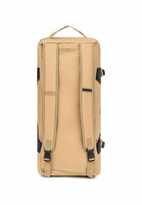 Sac de sport beige avec des bretelles rembourrées, une poignée supérieure, des accents noirs et des boucles latérales réglables ; fabriqué en tissu durable avec une texture lisse.