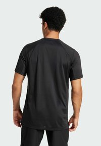 Zwart sportshirt met korte mouwen, voorzien van een gladde textuur, rechte zoom en raglanmouwen. Eenvoudig ontwerp zonder zichtbare logo's of patronen.