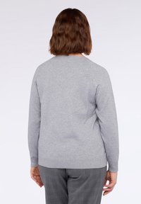 Maglione grigio con un knit testurizzato, caratterizzato da piccoli embellishments sparsi. Maniche lunghe e scollo rotondo con orli a coste.