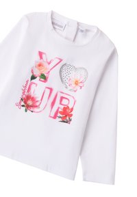 Camicia bianca a maniche lunghe con grafiche floreali, "YUP" in grassetto lettere rosa e un cuore metallico con strass. Texture in cotone morbido.