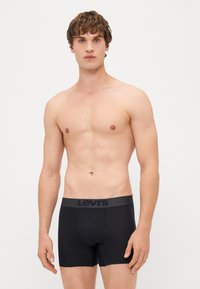 Fekete boxer alsónadrág szürke elasztikus derékkal, amelyen a "Levi's" logó található. Simogatós anyag, testhez álló fazon, combközép hosszúság.