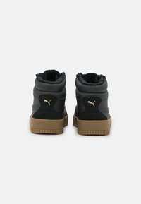 Svart höga sneakers med ett strukturerat mönster, foder av päls vid muddarna och en gummisula; har gyllene logotypdetaljer.