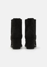 Bottines en daim noir à bout carré et talon bloc, avec des détails texturés et des panneaux latéraux élastiques.