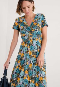 Blumenkleid mit einem dunklen Hintergrund und großen türkisfarbenen, orangen und lila Blumen. Kurze Ärmel und ein V-Ausschnitt-Design mit einem gerafften Bund.