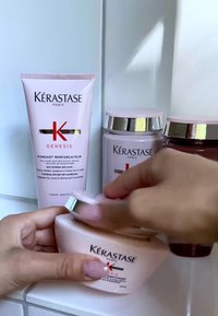 Vier Kérastase Haarpflegeprodukte, hauptsächlich in Pink mit silbernen Akzenten. Einschließlich einer Tube und zwei Töpfen, wobei einer der Töpfe geöffnet ist.