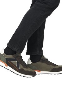 Grön och grå sneaker med en blandad materialdesign av mocka och mesh, svarta snören, orange detaljer och en vit sula.