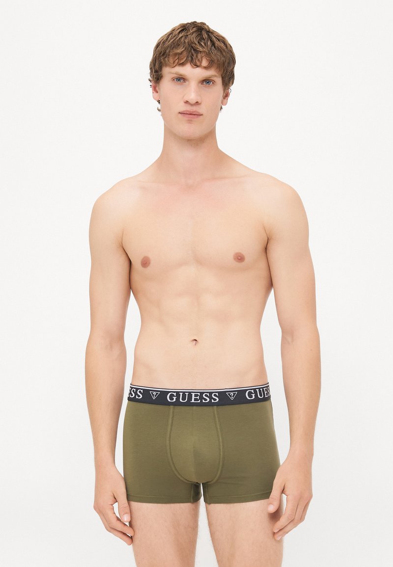 Olijfgroene herenboxershorts met een zwarte elastische tailleband waarop het "GUESS" logo in het wit staat. Glad materiaal en een strakke pasvorm.