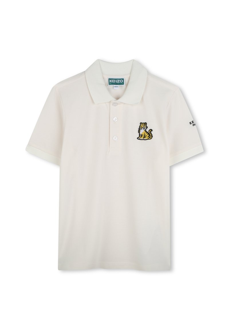 Polo en coton beige clair avec un col, trois boutons et un logo brodé de tigre sur la poitrine gauche. Manches courtes.