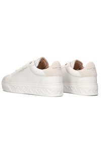 Bílé kožené tenisky s texturovanou platformou, zaoblenou špičkou a diskrétním logem na patě a boku pro minimalistický design.