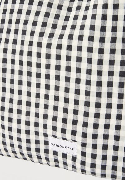 Υφασμα με ασπρόμαυρο καρό σχέδιο και μια ραμμένη ετικέτα υφάσματος κοντά στο κάτω άκρο, στην οποία αναγράφεται «MAISONÊTRE».