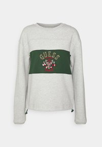 Šedá mikina s zeleným vodorovným pruhem, který obsahuje vyšívané logo "GUESS" a designové prvky, zahrnuje tkaničkové detaily na lemování.