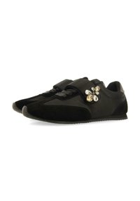 Sneakers neri a bassa fornitura con dettagli in suede, cinturini in velcro e un grappolo decorativo di gemme trasparenti e ambra sul lato.