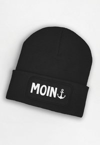 Black knit beanie with a wide, textured band. Features the word "MOIN" in bold white letters, accompanied by an anchor graphic.