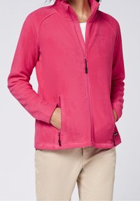 Pink fleece jacket with a high collar, two zippered pockets, and black zipper pulls. Soft texture and casual cut.