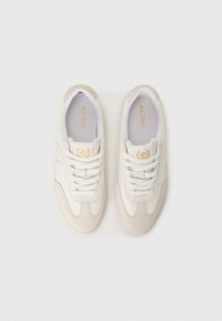 Baskets blanches avec une finition en cuir lisse et en suède, présentant un design à lacets, des accents de logo dorés et un bout arrondi.