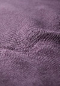 Tessuto viola testurizzato con un motivo intrecciato, caratterizzato da una superficie morbida e leggermente irregolare, che mette in risalto la sua qualità tattile e la gradazione dei colori.