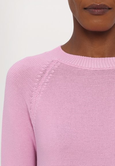 Vaaleanpunainen neulepusero, jossa on pyöreä pääntie, teksturoitu kangas ja raglan-hihat. Sisältää hienovaraisen kuvion koko ajan.
