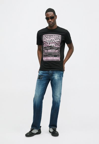 Čierne tričko s grafickým potlačou v ružovej farbe a textom. Svete modré džínsy s opotrebovanými detailmi a čierne tenisky s bielymi pruhmi.