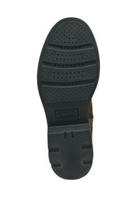 Semelle de chaussure en caoutchouc noir avec un motif en relief, comportant des perforations pour la respirabilité. Logo de la marque estampillé au centre.