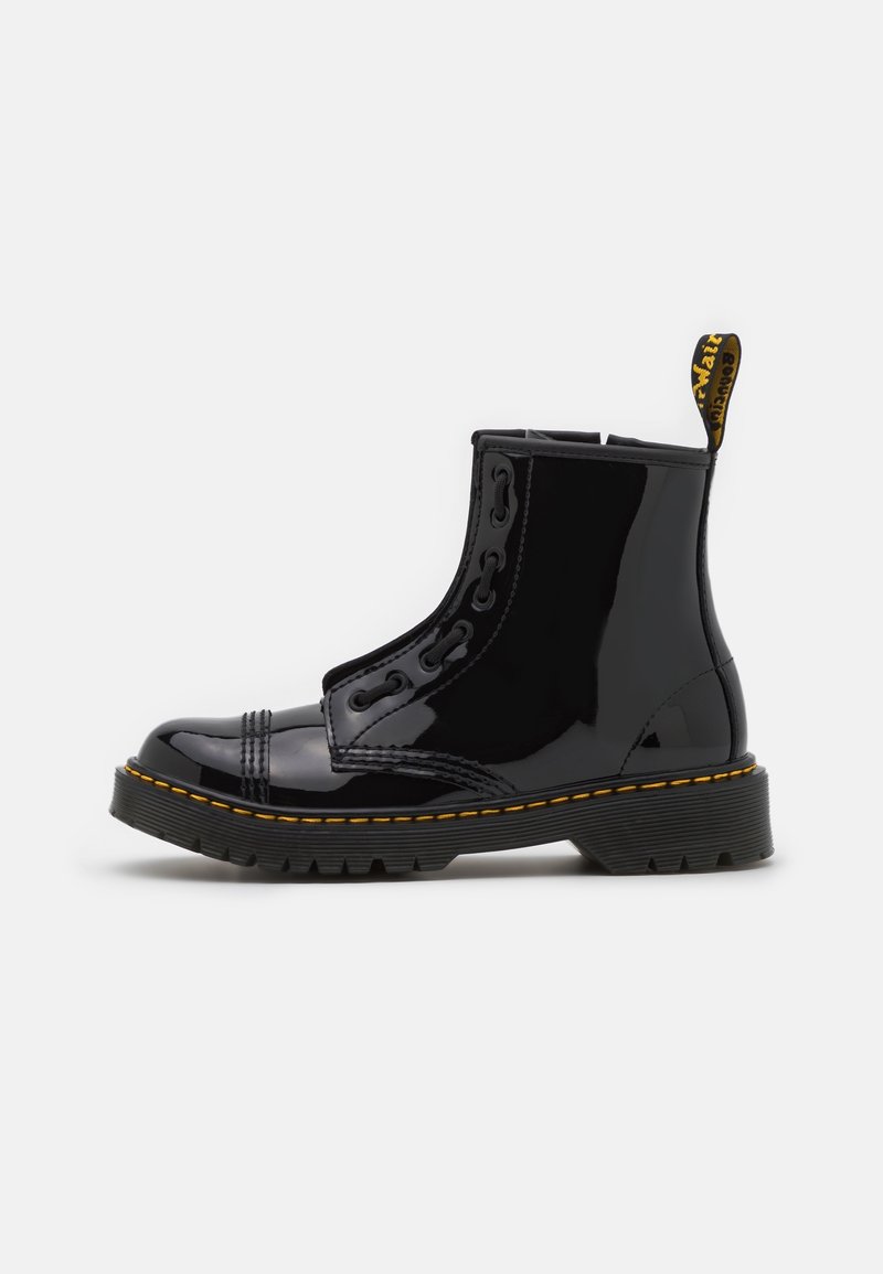 Bottines en cuir verni noir avec fermeture éclair latérale, bout rond, surpiqûres jaunes et semelle en caoutchouc texturée. Talon renforcé et languette de maintien.