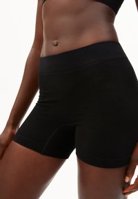 Shorts noirs sans coutures en tissu extensible, dotés d'une ceinture large, d'une texture côtelée et d'une coupe ajustée pour le confort.
