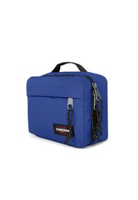Modrá textilní taška obdélníkového tvaru, s horním uchopovacím popruhem, dvěma zipovými přihrádkami a předním štítkem s logem značky.