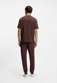 Chemise à manches courtes texturée effet gaufré marron avec pantalon assorti, présentant une coupe décontractée et des poignets côtelés, porté avec des chaussettes blanches.