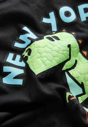 Schwarzes T-Shirt mit einem grünen Dinosaurier-Graphic, der strukturierte Schuppen aufweist, und blauer Typografie mit dem Schriftzug "NEW YORK" in fetten Buchstaben.