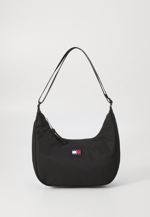 Czarna nylonowa torba na ramię o zakrzywionym kształcie, z regulowanym cienkim paskiem, zamkiem błyskawicznym i małą naszywką z logo Tommy Jeans z przodu.